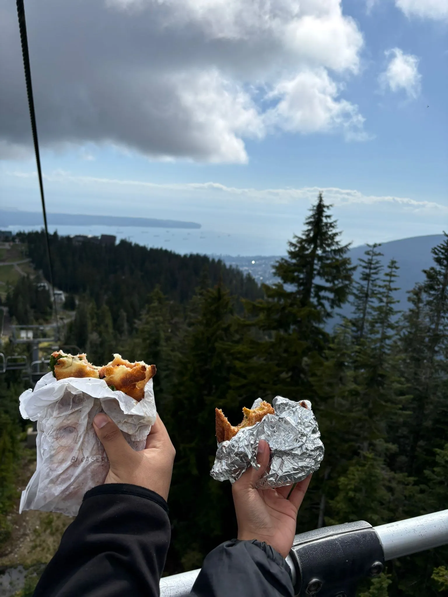 Two sandwiches held up on the Grouse Mountain chairlift above Vancouver